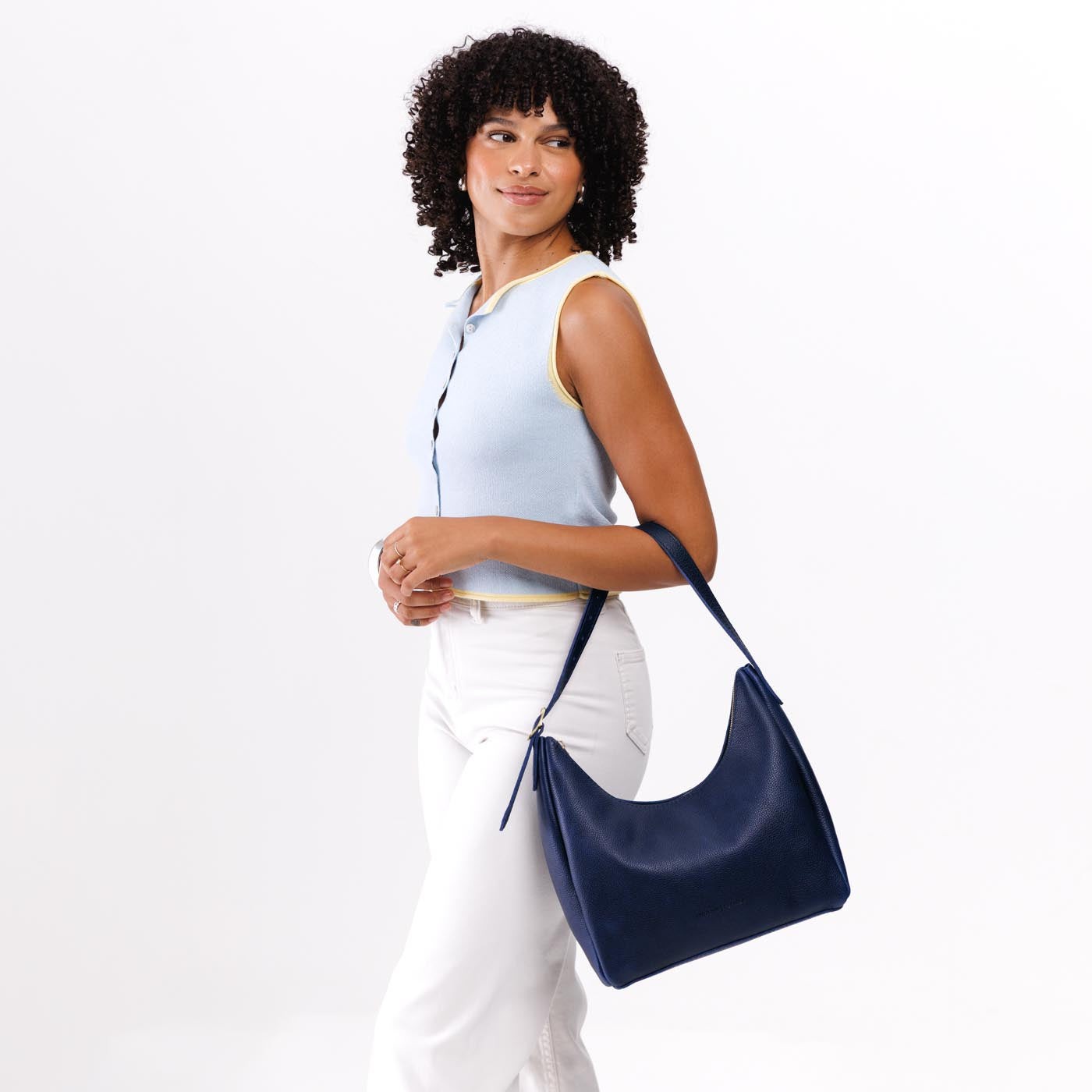 Cobalt*Medium | Model holding u-shaped, flat-bottomed leather shoulder bag with adjustable strap