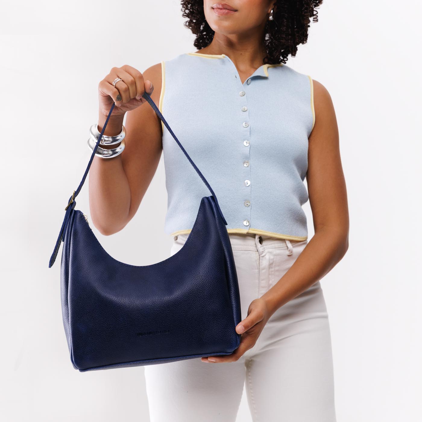Cobalt*Medium | Model holding u-shaped, flat-bottomed leather shoulder bag with adjustable strap