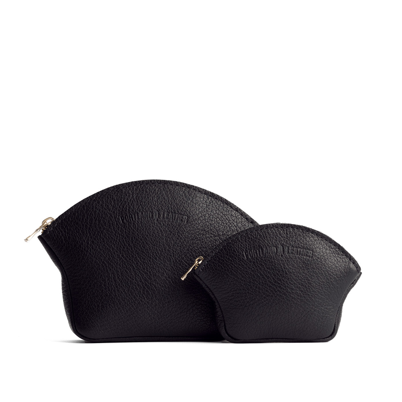 Pebbled--black | Comparison shot of small and large seashell shaped leather makeup bags with curved top zipper and flat bottom