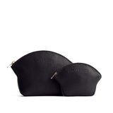 Pebbled--black | Comparison shot of small and large seashell shaped leather makeup bags with curved top zipper and flat bottom