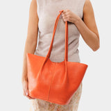 Koi Large | Model holding wide bucket shaped tote bag with matching leather handles