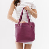 Iris | Model holding leather tote bag with riveted straps and exterior key loop 
