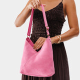 Pink Suede Small | Model holding petite shoulder bag with adjustable strap and magnetic snap closure