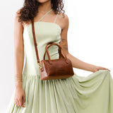 Nutmeg Small | Model wearing mini duffle shaped handbag with crossbody strap