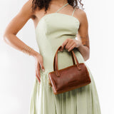 Nutmeg Small | Model wearing mini duffle shaped handbag with crossbody strap