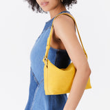 Hello Yellow Small | Model wearing petite slouchy leather shoulder bag with zipper opening and three metal tree emblems