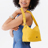 Hello Yellow Small | Model holding petite slouchy leather shoulder bag with zipper opening and three metal tree emblems