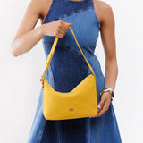 Hello Yellow Small | Model holding petite slouchy leather shoulder bag with zipper opening and three metal tree emblems