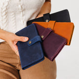 All Variants | Model holding four different colored wallets with snap closures